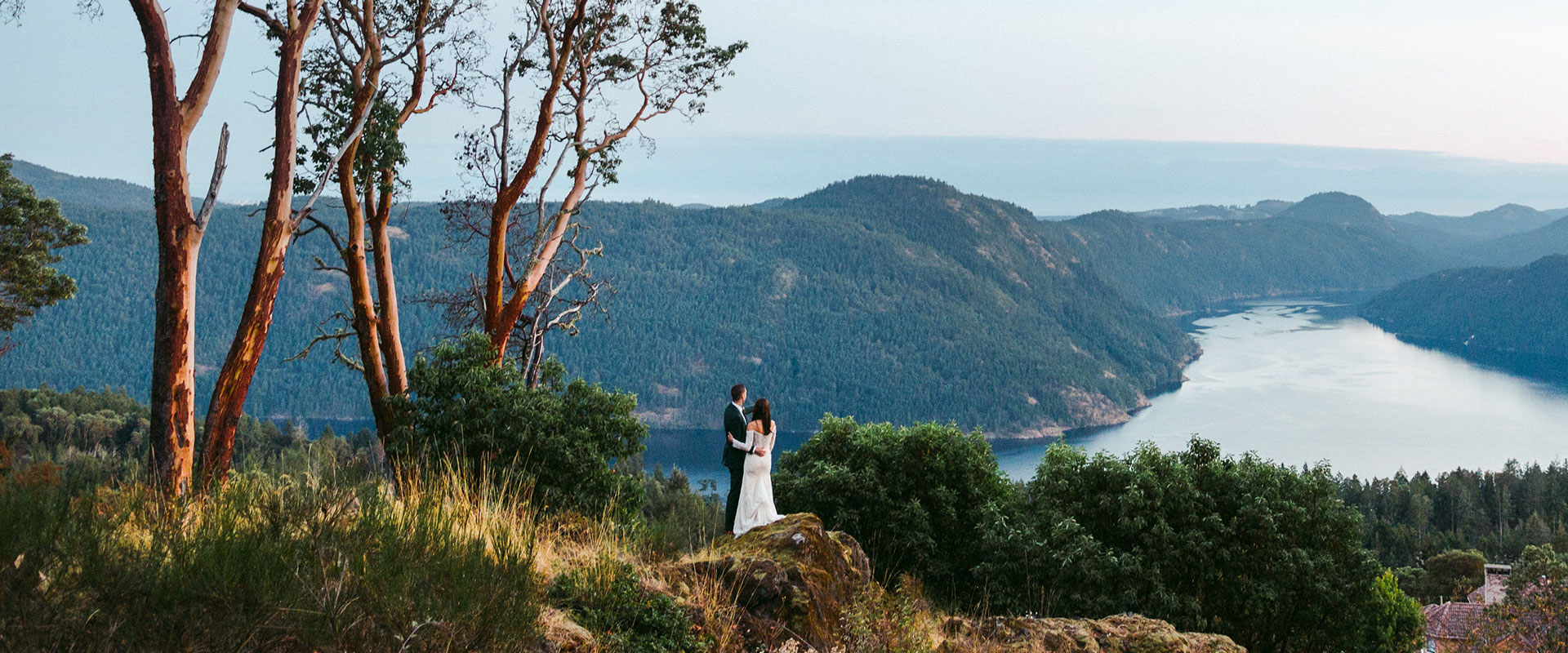 A newly wed couple looking out at the sweeping view of the mountains and ocean of the Saanich inlet.