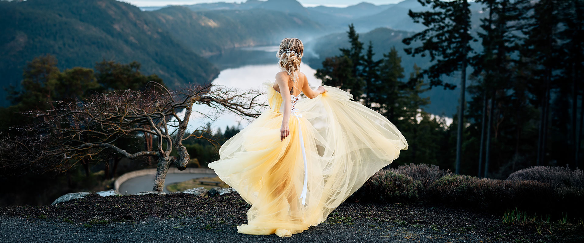 A woman in a beautiful yellow dress with the Saanich inlet backdrop by Calabrese photography.
